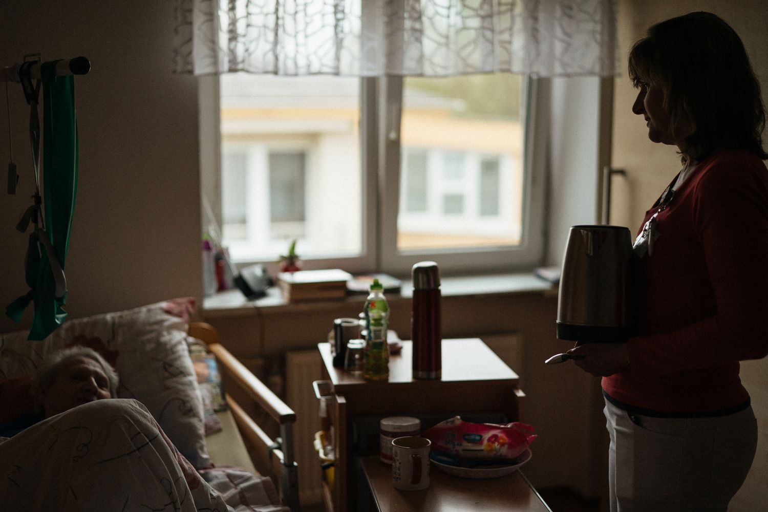 An adult son sits at a kitchen table with a notepad, working through the calls to hire a caregiver.